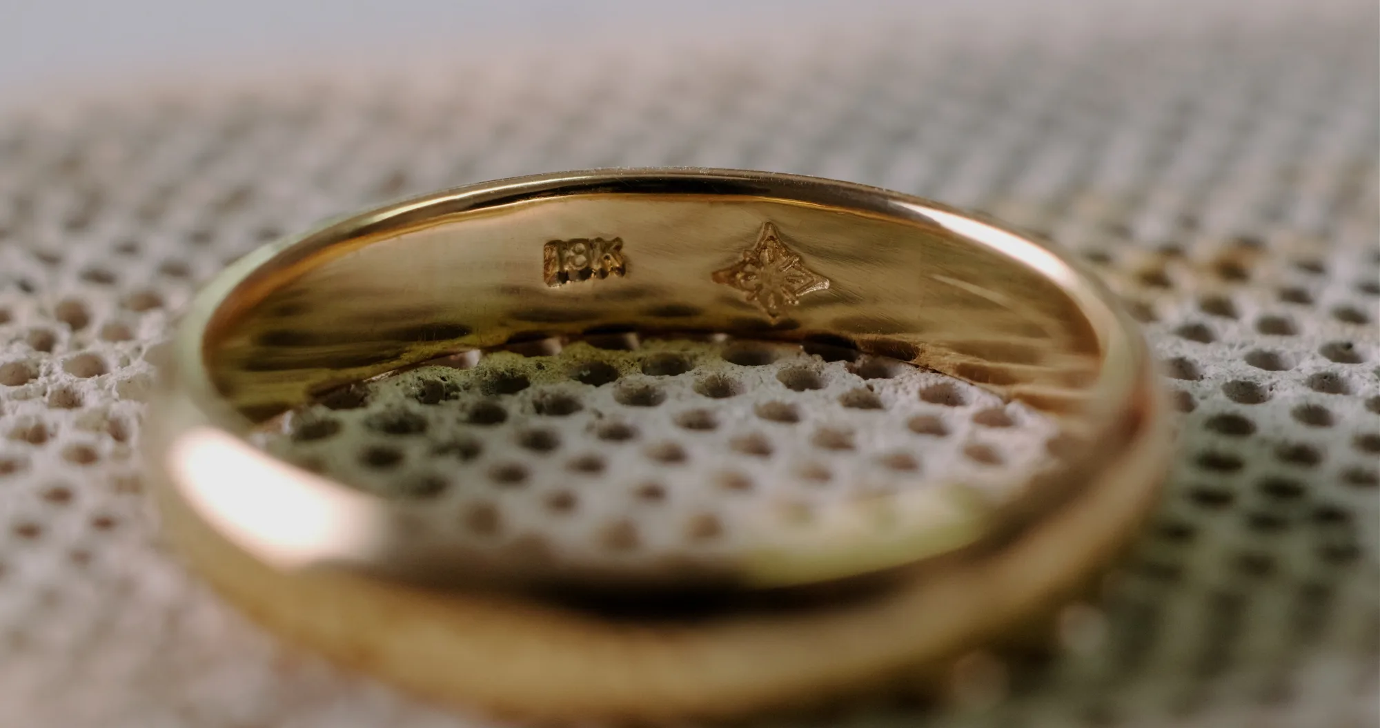 Interior de una argolla de oro Liévano mostrando el sello «18K» y el logotipo de la casa